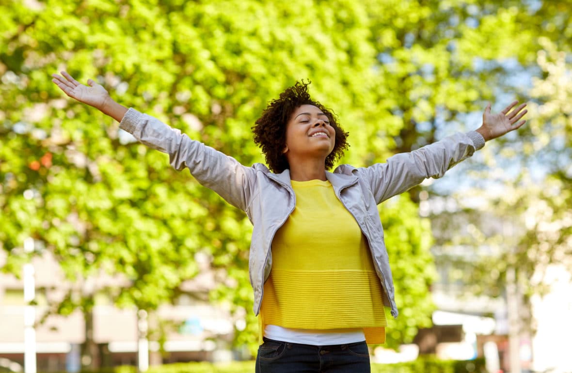 A person standing outdoors with arms open